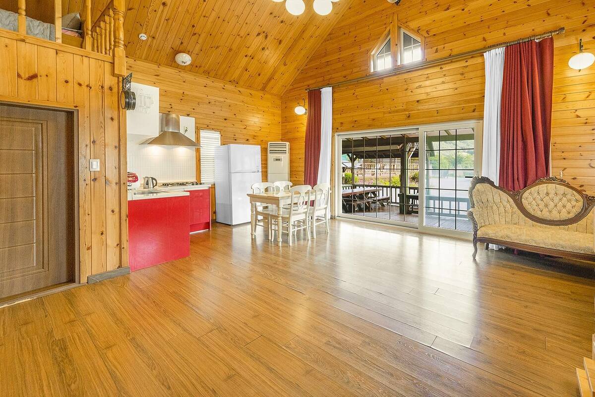 A wooden interior with a kitchen, dining area, and a staircase.