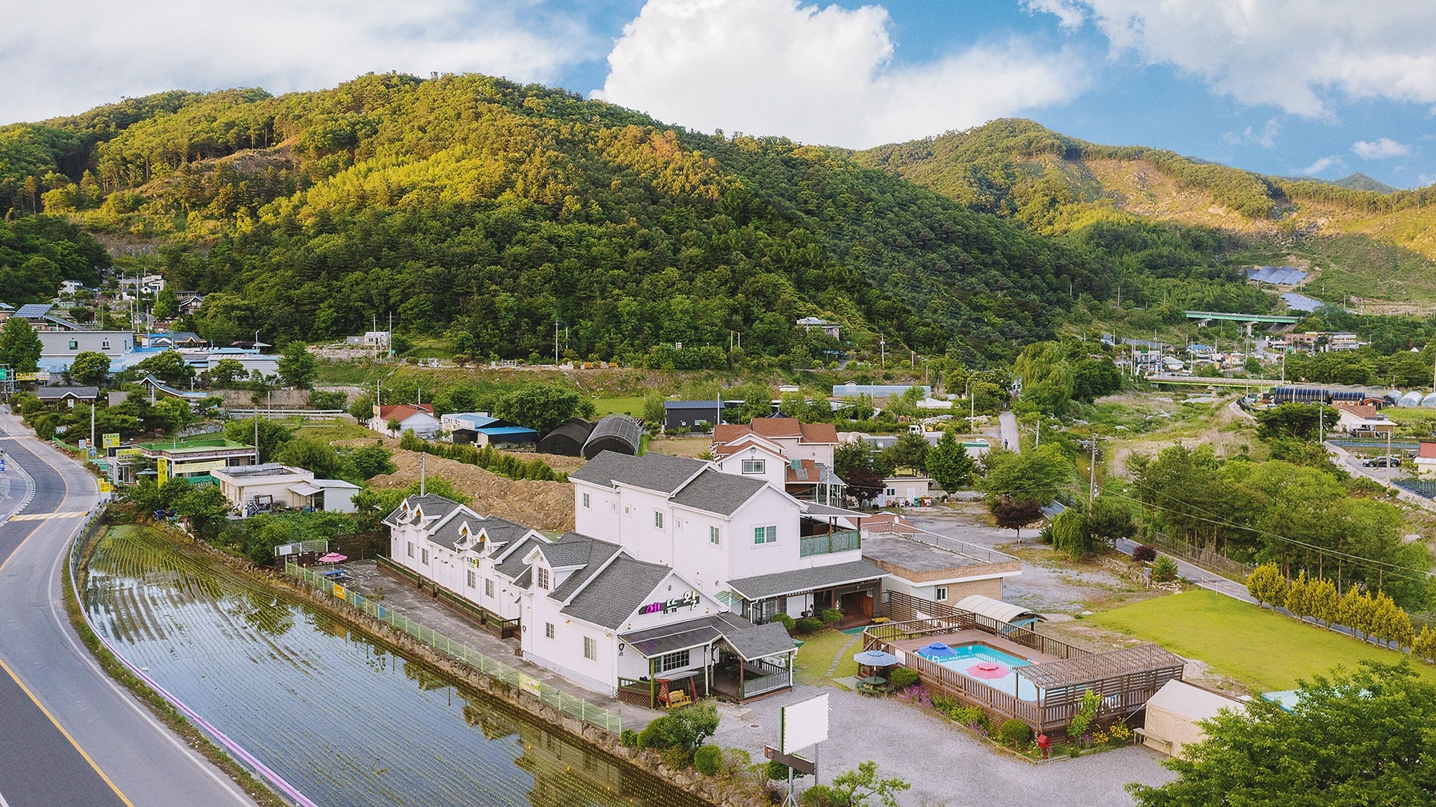 A coastal property with a swimming pool, a tennis court, and a view of the sea.