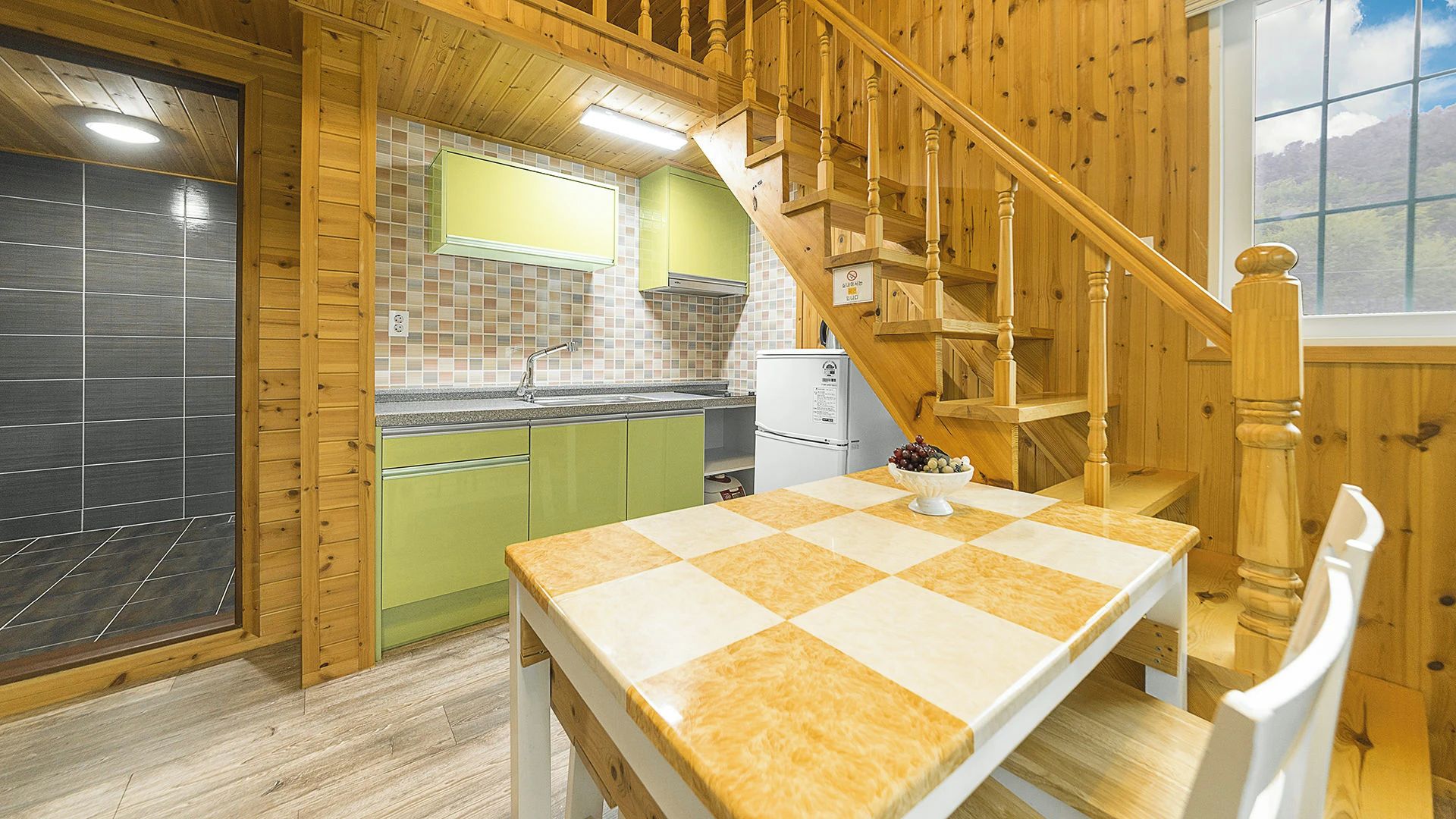 Ein Holzinnenraum mit einer Küche, einem Esstisch und einer Treppe.