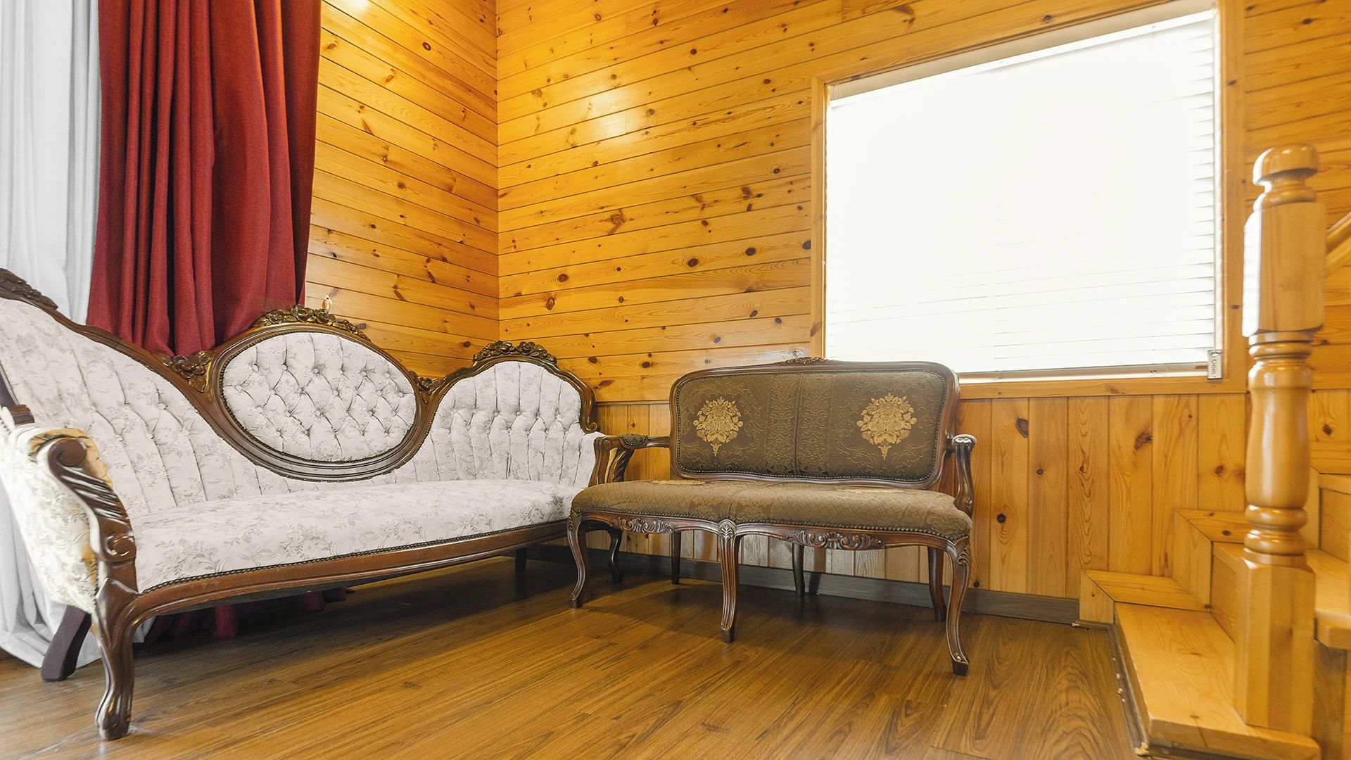 Ein Zimmer mit Holzwänden und Holzboden, mit zwei gepolsterten Sesseln mit aufwendigen Verzierungen.