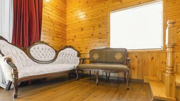 Ein Zimmer mit Holzwänden und Holzboden, mit zwei gepolsterten Sesseln mit aufwendigen Verzierungen.