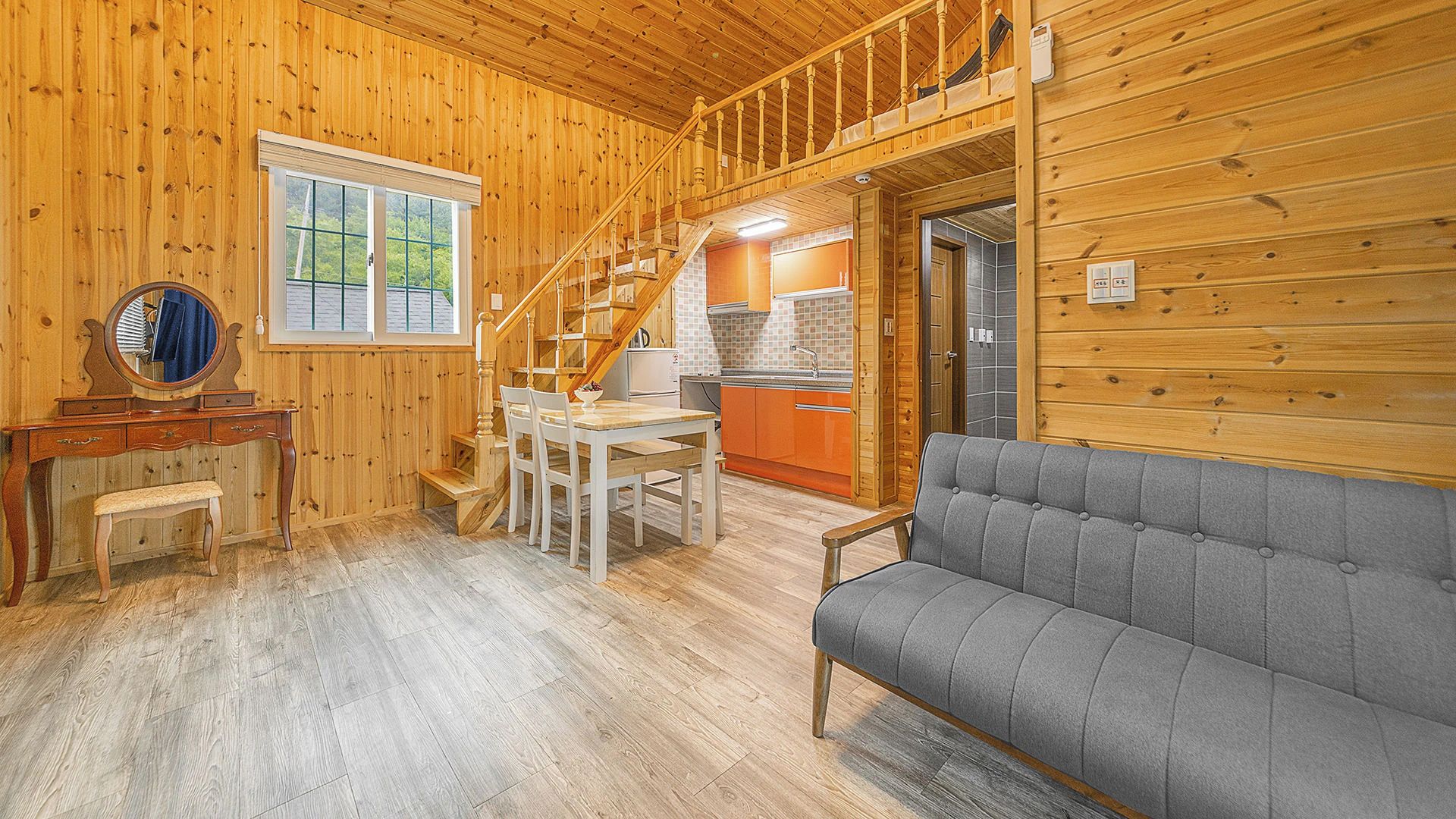 A wooden interior with a dining area, sofa, and kitchen.