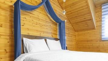 A wooden cabin room with a four-poster bed, white bedding, and blue curtains.