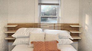 Un lit avec une tête de lit en bois, une literie blanche et une fenêtre au-dessus.