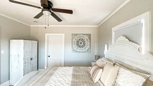 A bedroom with a bed, a ceiling fan, a door, and a wall decoration. - Clean, Modern Cottage near Martinsville! (Fieldale)