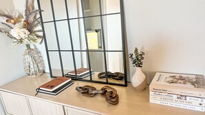 A vanity with a mirror, books, a vase with flowers, and a pair of shoes. - Clean, Modern Cottage near Martinsville! (Fieldale)