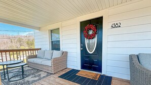 A porch with a wicker sofa, a small table, and a welcome mat. - Clean, Modern Cottage near Martinsville! (Fieldale)