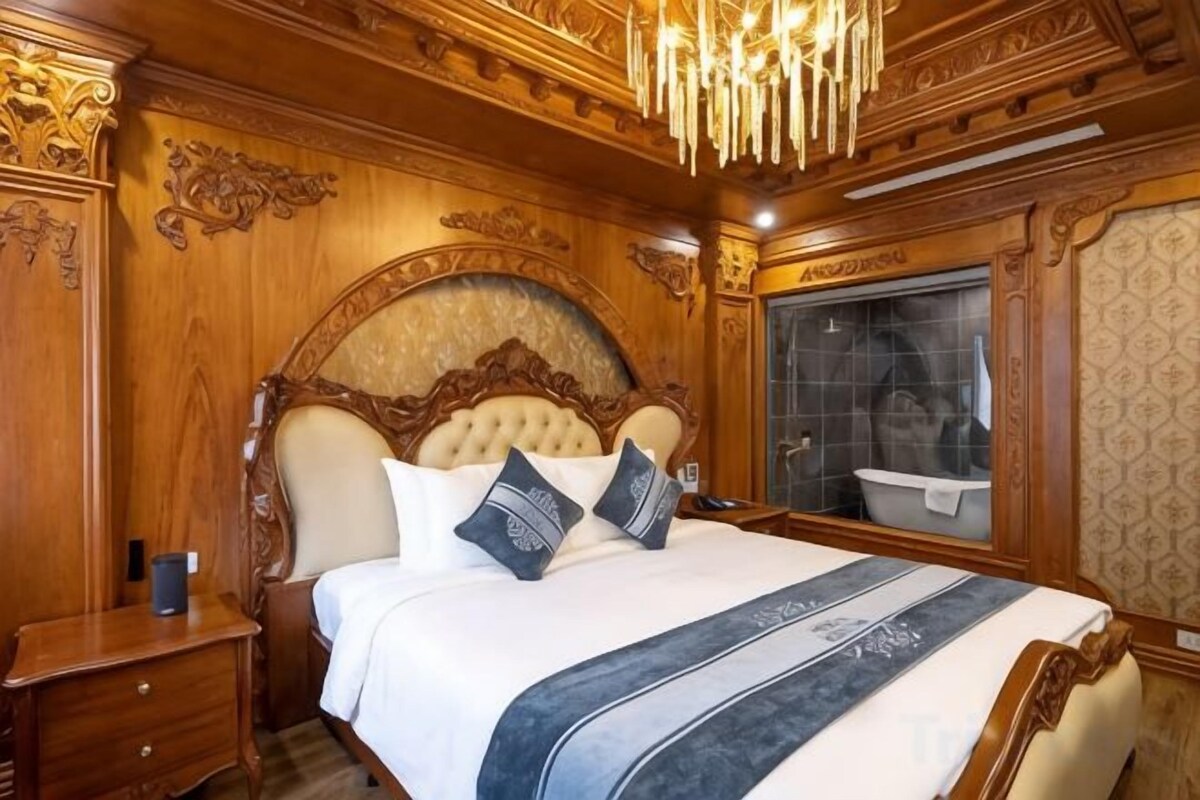 Un dormitorio lujoso con una cama grande, un elaborada cabecera de madera y un candelabro.