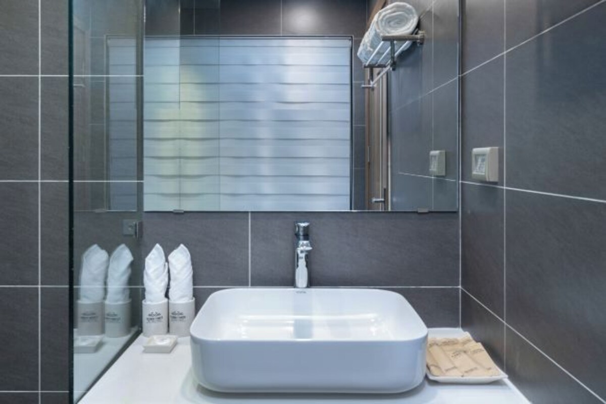 A modern bathroom with a large rectangular sink, a glass shower enclosure, and a mirror above the sink.