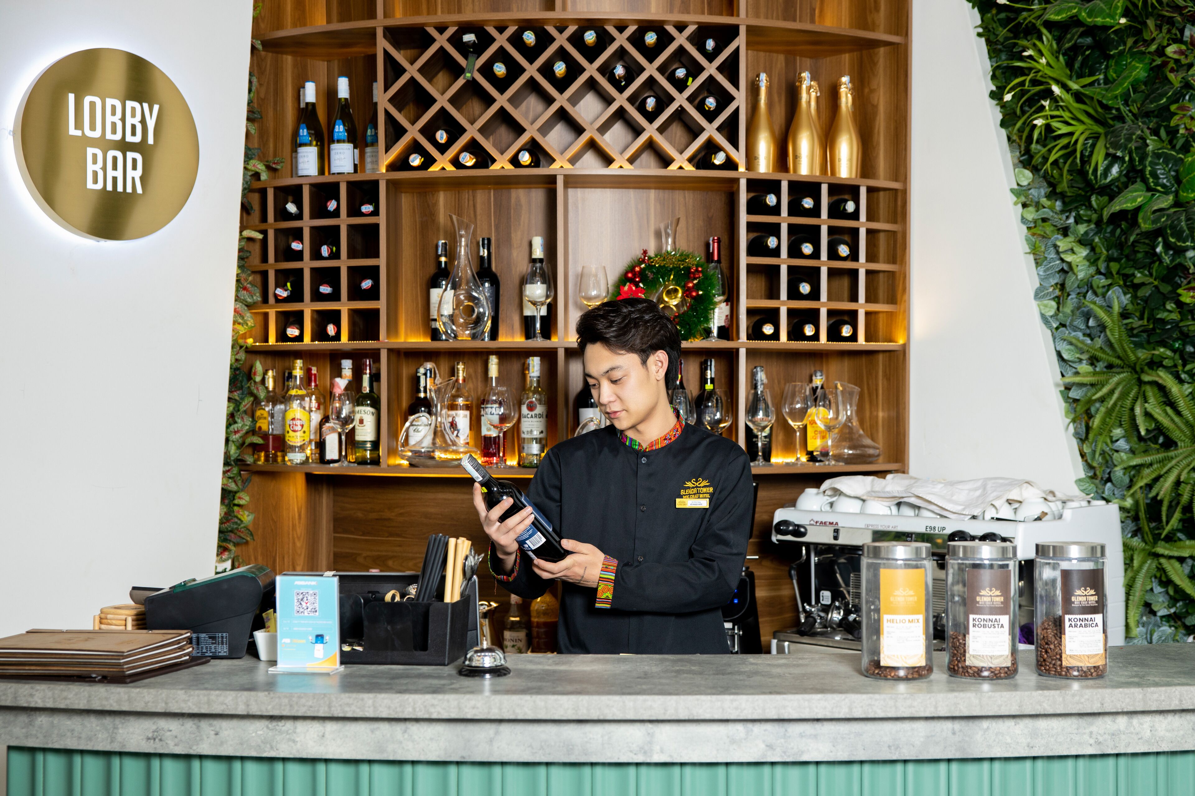 A bar area with a bartender holding a bottle, shelves with various bottles, and coffee containers.