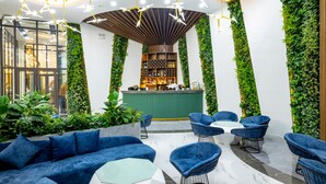A modern lounge area with a bar, blue seating, and green vertical gardens. - Glenda Tower Moc Chau Hotel (Moc Chau)