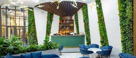 Un área de lounge moderna con bar, asientos azules y jardines verticales verdes.