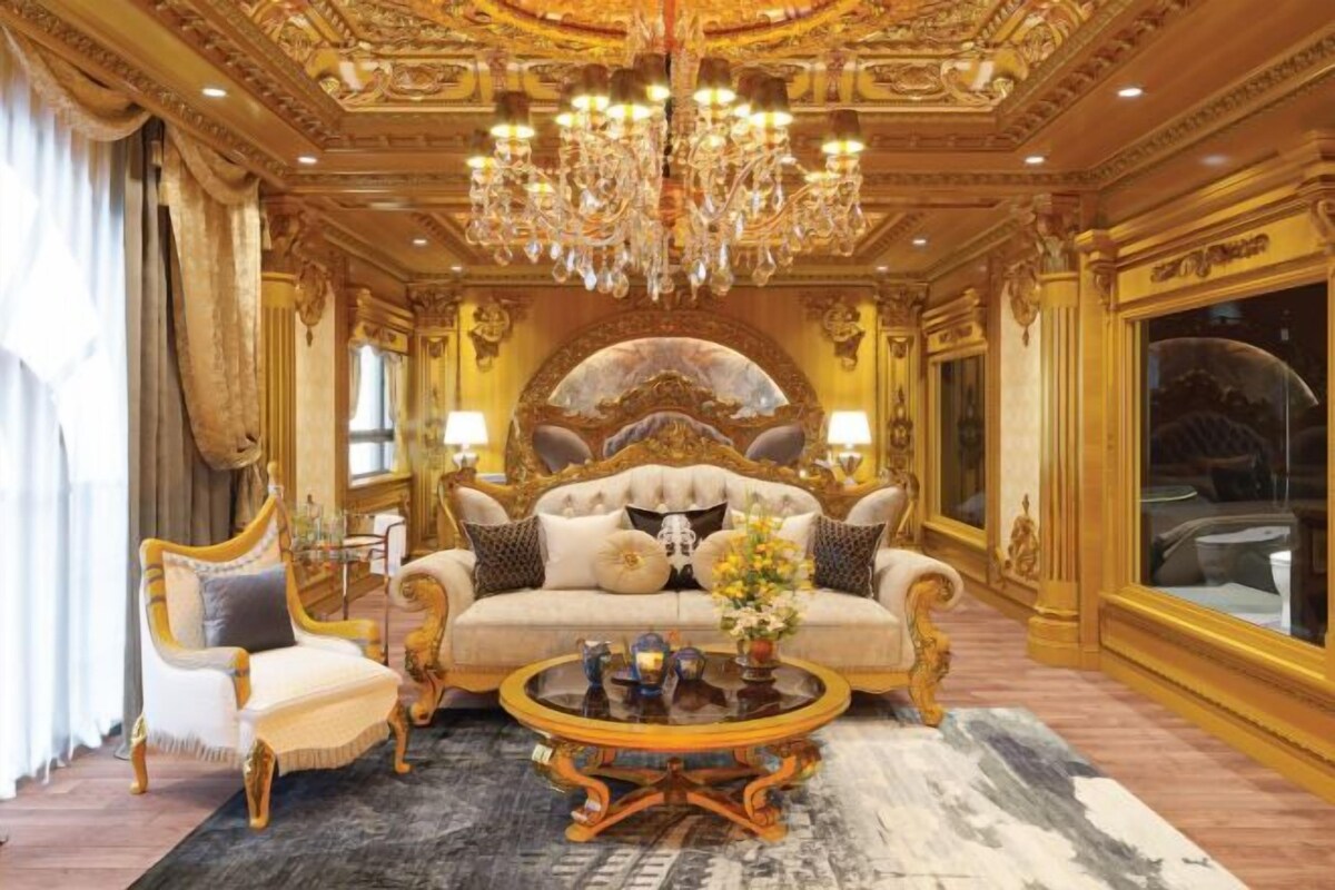 An opulent room with a grand chandelier, a plush sofa, a classic armchair, and a coffee table.
