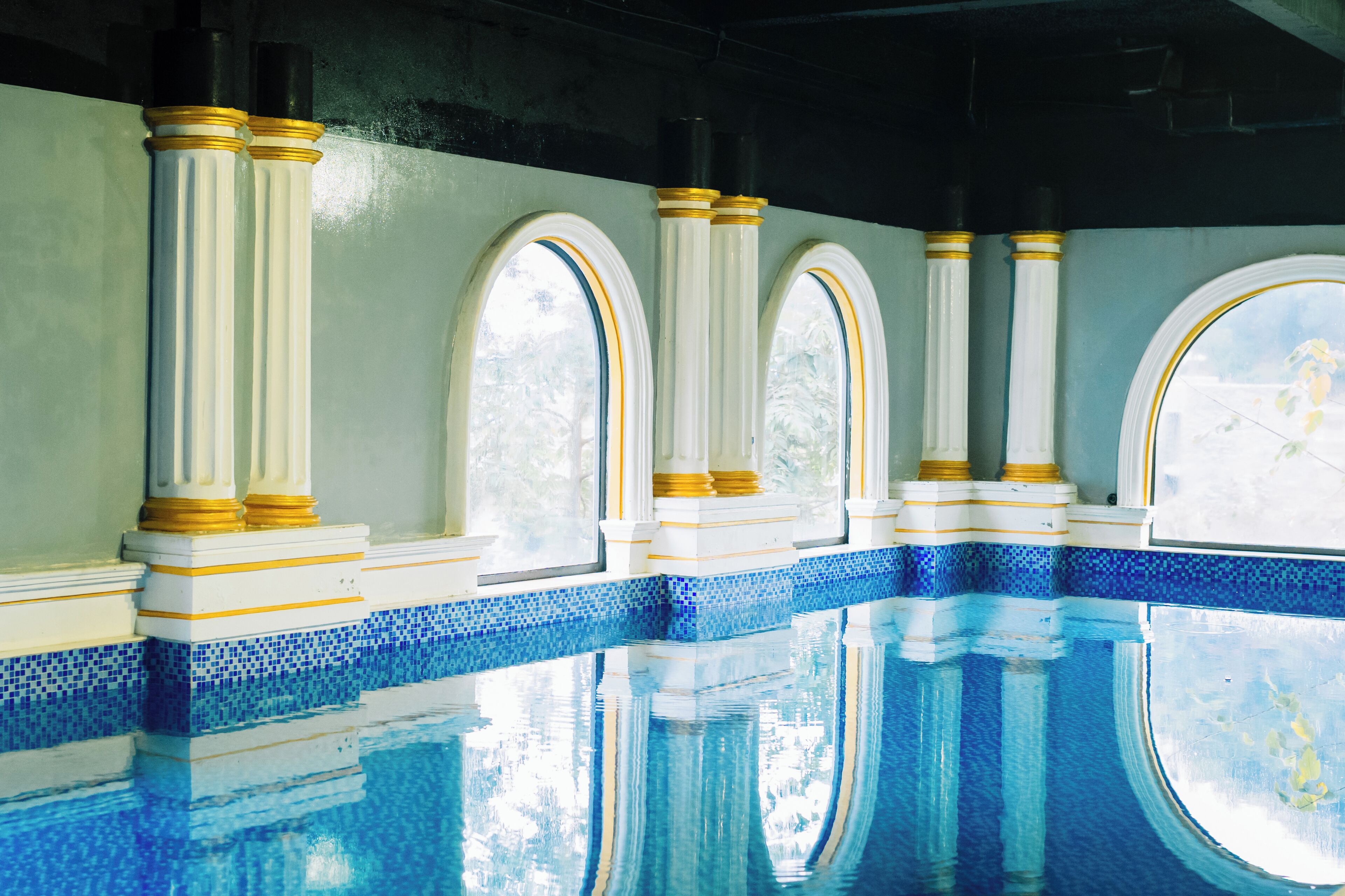 A swimming pool with white columns and blue mosaic tiles.