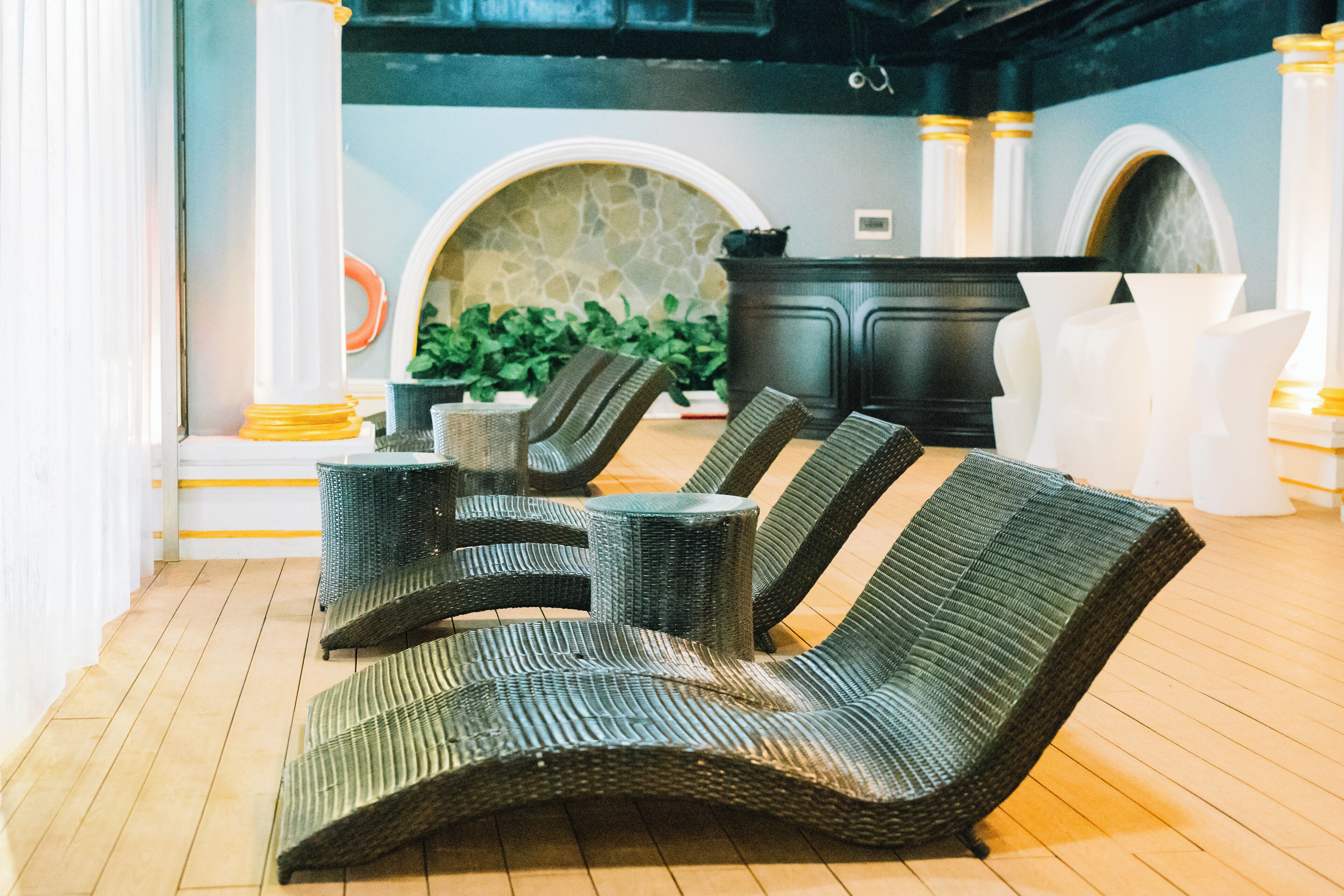 A lounge area with wicker lounge chairs, a stone wall, and a fireplace.