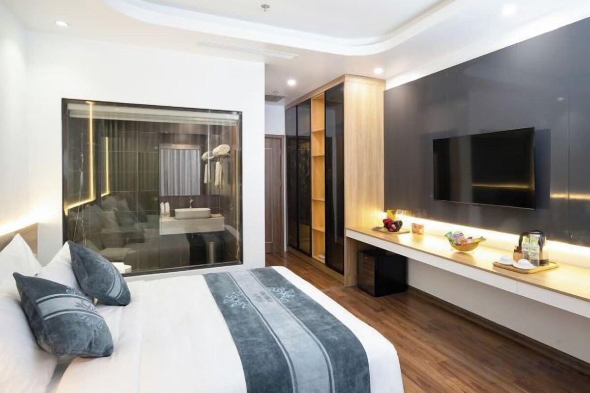 Quarto moderno com cama grande, TV na parede e closet espaçoso.