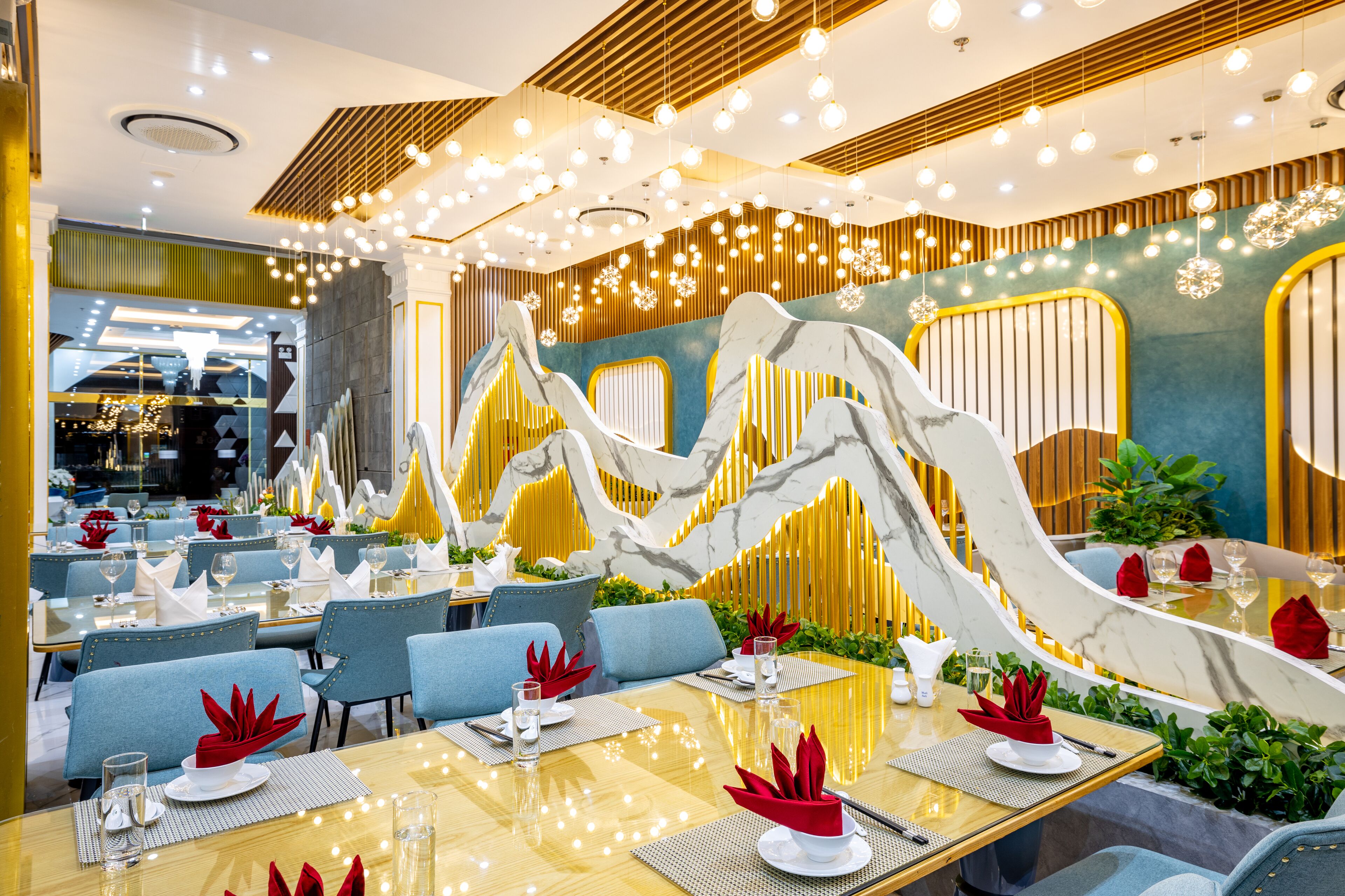 Um restaurante moderno com design limpo e contemporâneo, apresentando uma parede central de mármore, assentos azuis e iluminação acolhedora.