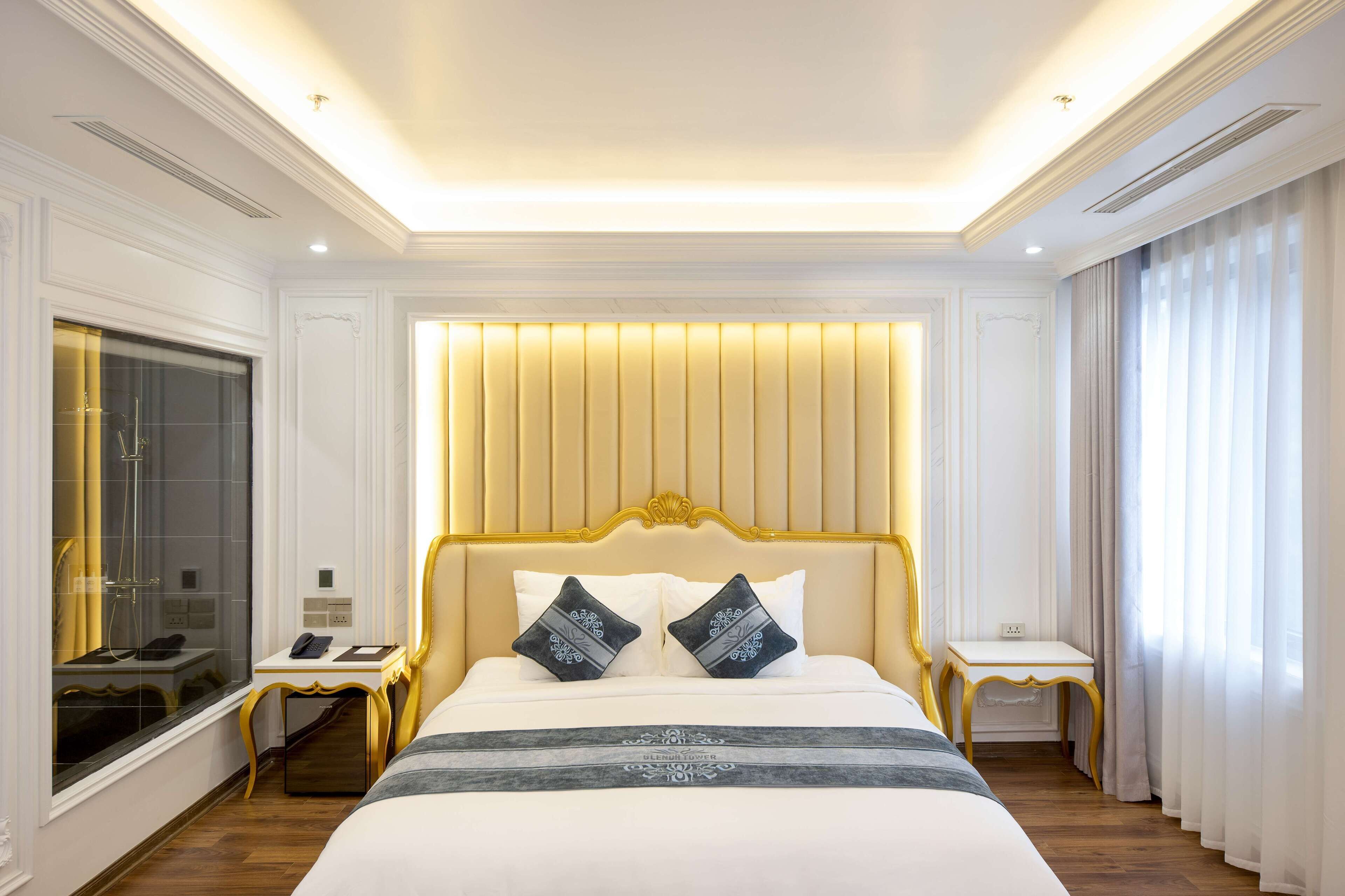 A hotel room with a large bed, a bedside table, a mirror, and a window with curtains.
