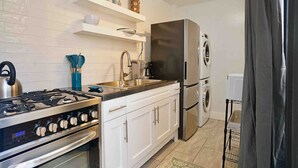 A modern kitchen with white cabinets, stainless steel appliances, and a built-in oven. - Ocean View Studio • by Magen's • Pool & Generator (Northside)