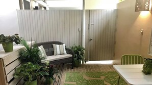 A patio with a wicker sofa, a dining table, and potted plants. - Ocean View Studio • by Magen's • Pool & Generator (Northside)