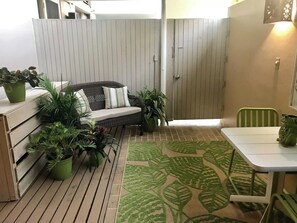 A patio with a wicker sofa, a dining table, and potted plants. - Ocean View Studio • by Magen's • Pool & Generator (Northside)