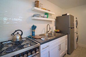 A modern kitchen with a gas stove, stainless steel sink, and a built-in refrigerator.