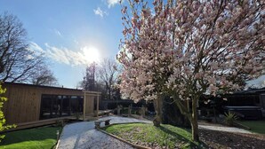 A garden with a wooden structure, a pathway, and a tree with pink blossoms. - Lighthouse Lodge Dog Friendly Nr Sutton on Sea (Sutton on sea)