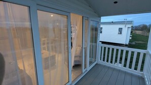 A covered porch with sliding glass doors leading to a patio area. - Lighthouse Lodge Dog Friendly Nr Sutton on Sea (Sutton on sea)