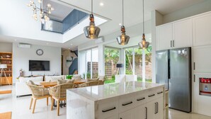 A modern kitchen with a central island, white cabinetry, and pendant lighting. - Villa Ammanya (Canggu)