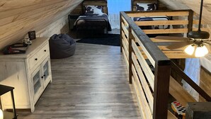A cozy attic bedroom with a sloped ceiling, wooden bunk beds, a small desk, and a nightstand. - Peaceful cabin in the center of riding country!  (Duff)