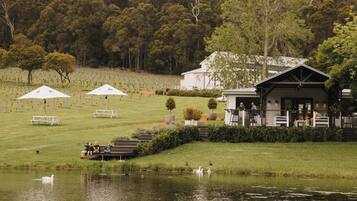 A lakeside setting with a building, picnic tables, and a grassy area.