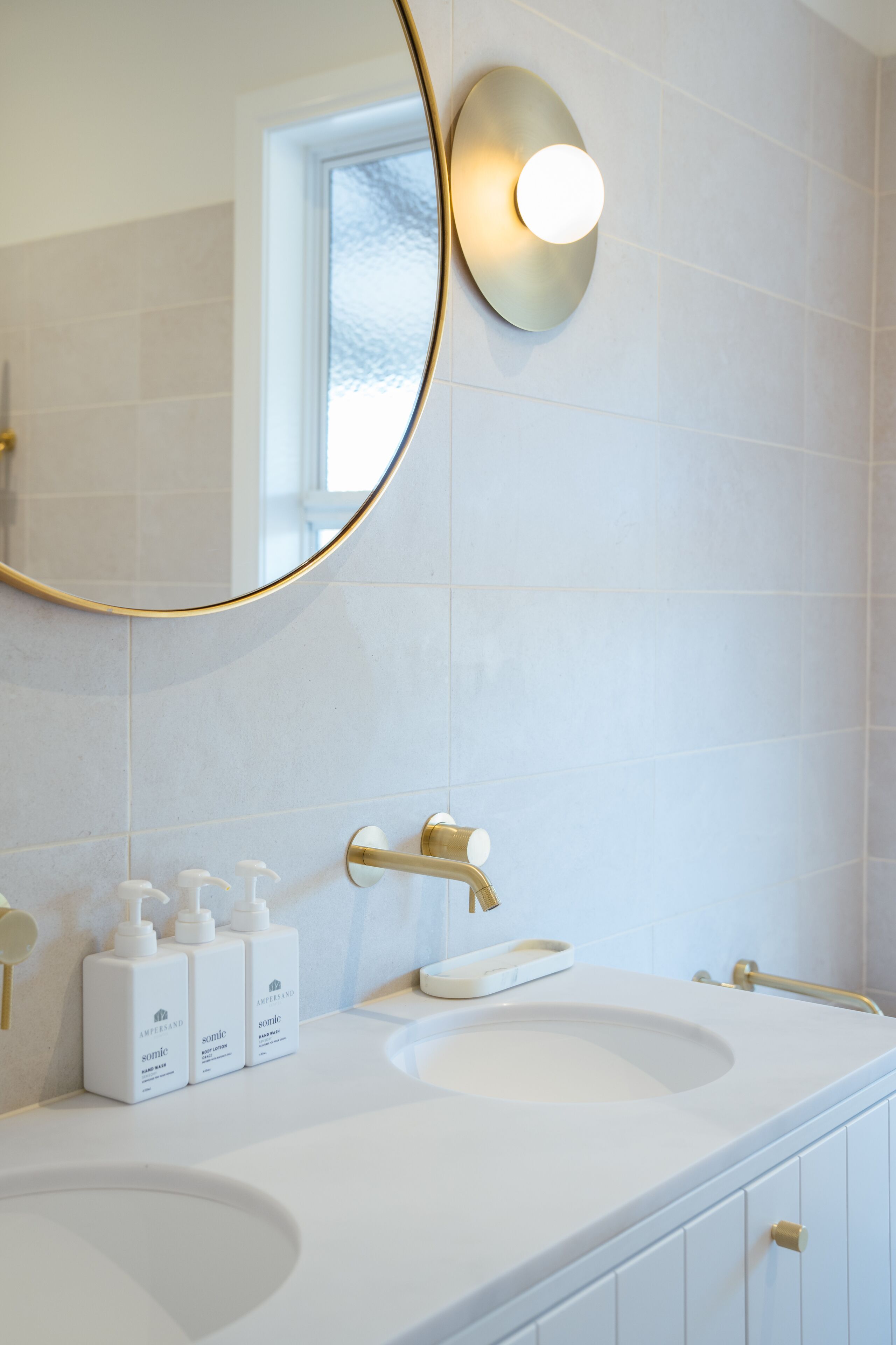 A bathroom with a white sink, gold fixtures, and a large mirror with a gold frame.