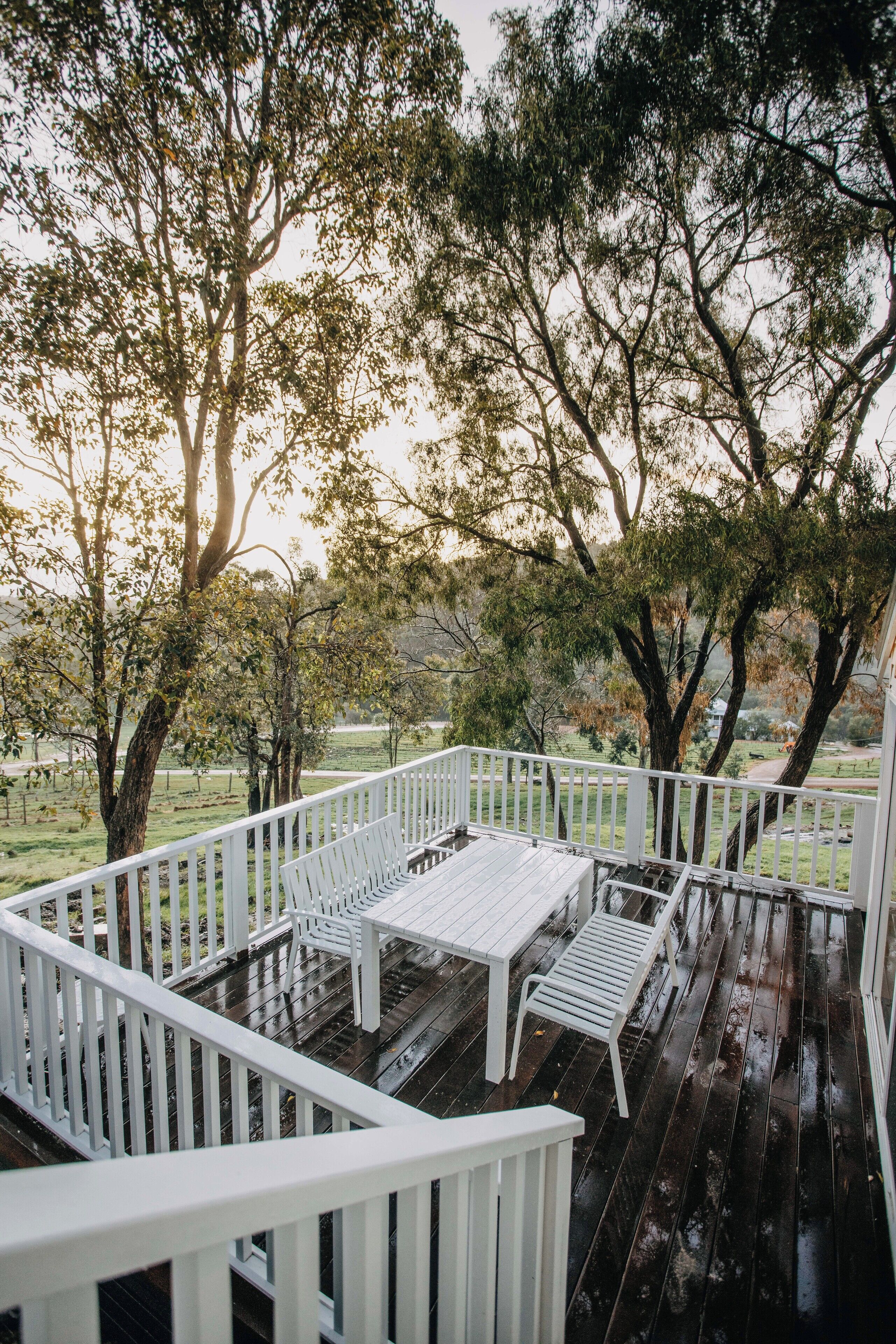 A wooden deck with white railings, a bench, and a table.