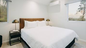 A neatly made bed with white linens and a wooden headboard, flanked by two bedside tables with lamps.