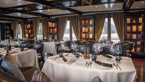 A restaurant with tables set for dining, featuring a view of the water outside. - Paradise Sails Cruise Ha Long (Ha Long)