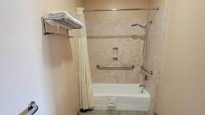 Un baño estrecho con bañera, ducha y un perchero para toallas.