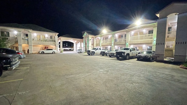 Un estacionamiento con varios autos y un edificio con múltiples balcones y una entrada principal.