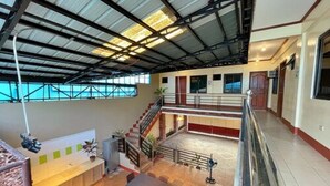 A spacious indoor area with a high ceiling, a staircase, and a reception desk. - Weekdays Hot Spring Resort by Cocotel (Calamba)