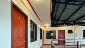A corridor with a tiled floor, wooden doors, and a metal railing. - Weekdays Hot Spring Resort by Cocotel (Calamba)