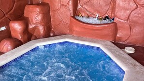 Ett bubbelbad med en vägg av stenblock som bakgrund och en kant av kakel.