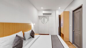 A hotel room with a bed, a wooden headboard, a wardrobe, and a door. - UPAR Hotels Uthandi ECR (Chennai)