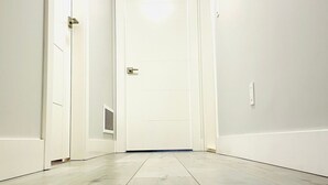 A narrow hallway with white walls and a white door at the end. - Stylish, clean&cozy new 2 bedroom guest suite (Abbotsford)