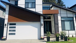 A modern two-story house with a large garage, a wooden front door, and a number 2706 on the side. - Stylish, clean&cozy new 2 bedroom guest suite (Abbotsford)