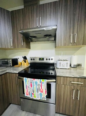 Uma cozinha com armários de madeira, fogão de aço inoxidável, torradeira e micro-ondas.
