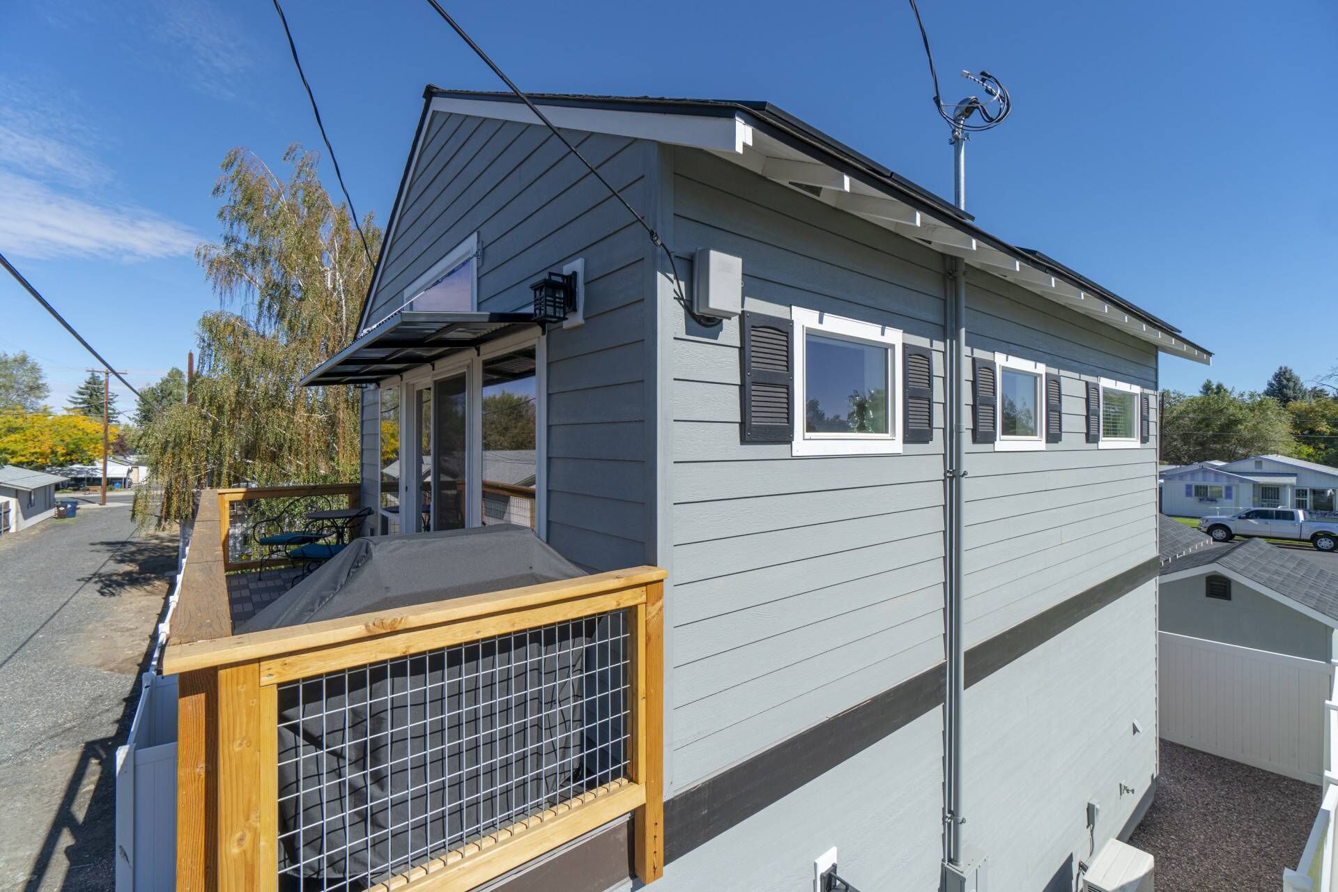 A single-story mobile home with a front deck, a small attached garage, and a satellite dish.