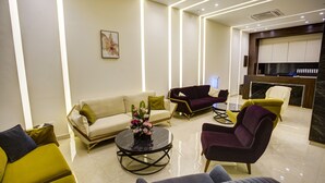A modern hotel lobby with a sofa, armchairs, a coffee table, and a reception desk. - AQABA COAST HOTEL (Aqaba)