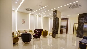 A modern lobby with a sofa, armchairs, and a marble reception desk. - AQABA COAST HOTEL (Aqaba)