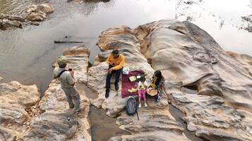 Un groupe de personnes est assis sur un terrain rocheux, près d’une étendue d’eau.