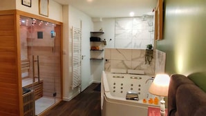 A modern bathroom with a glass shower enclosure, a white bathtub, and a marble backsplash.