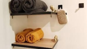 A wall with three wooden shelves, each holding different items.